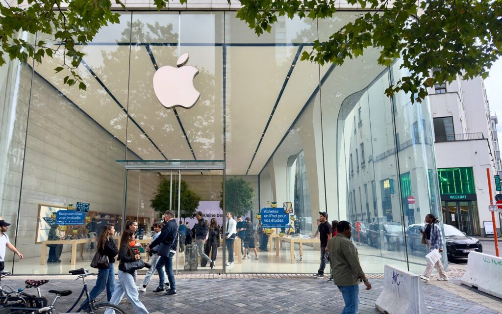 Façade vitrée de l’Apple Store de Bruxelles avec le logo Apple, passants sur le trottoir