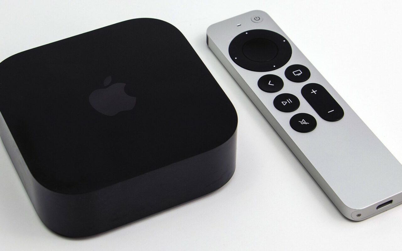 Un boitier Apple TV 4K noir pose a cote de la telecommande Siri Remote argentee, sur fond blanc