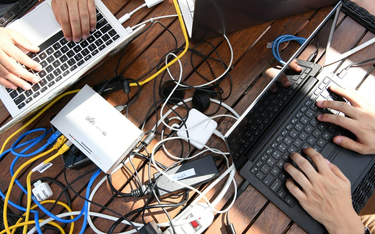 Table encombree de cables reseau, de blocs d'alimentation et d'un ordinateur portable ouvert, lors d'un atelier de securite informatique