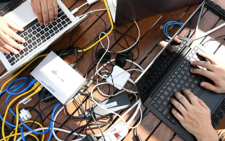 Table encombree de cables reseau, de blocs d'alimentation et d'un ordinateur portable ouvert, lors d'un atelier de securite informatique