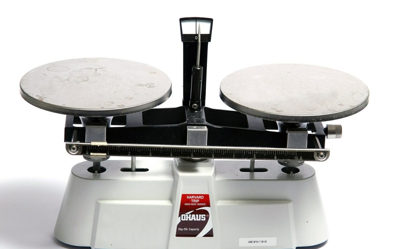 Une balance de laboratoire a deux plateaux metalliques sur fond blanc