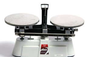 Une balance de laboratoire a deux plateaux metalliques sur fond blanc