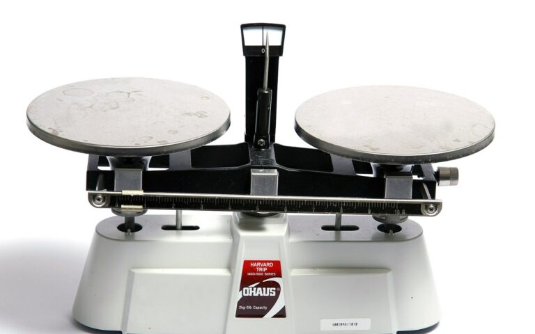 Une balance de laboratoire a deux plateaux metalliques sur fond blanc