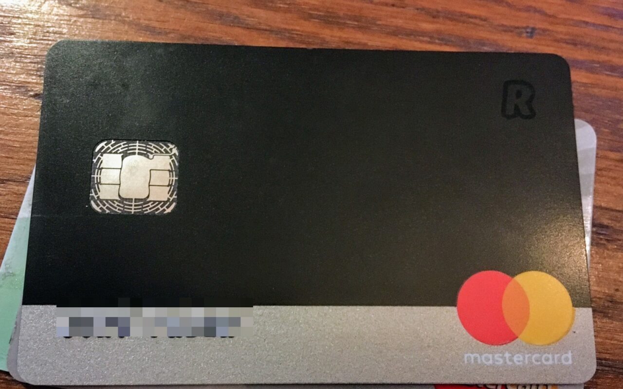 Une carte bancaire Revolut noire, posée sur une table en bois, le nom du titulaire ayant été rendu illisible.