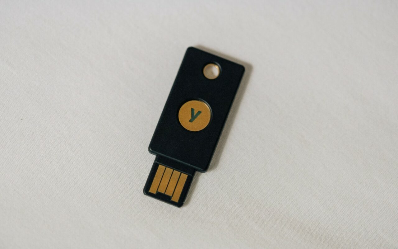 Une clé de sécurité matérielle au format USB, tenue entre deux doigts.