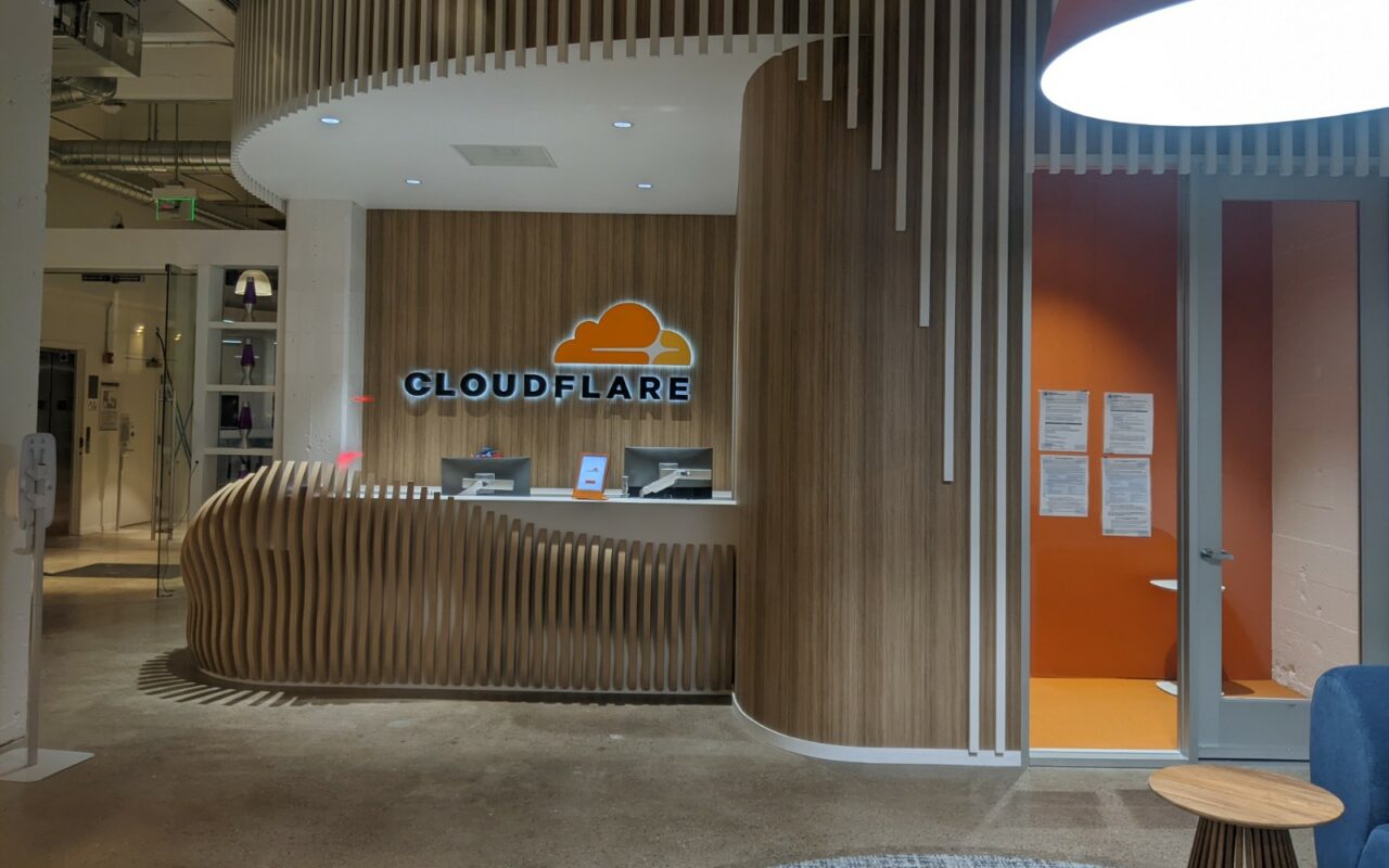 Comptoir d'accueil surmonté du logo Cloudflare, dans le hall d'entrée d'un bureau de l'entreprise