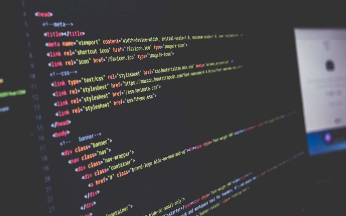 Lignes de code colorées affichées sur un écran d’ordinateur dans une pièce sombre