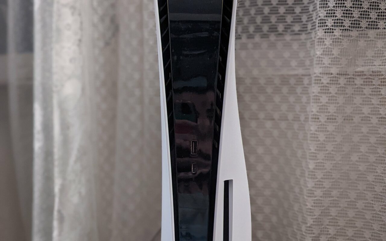 Console PlayStation 5 blanche posee a la verticale a cote de sa manette