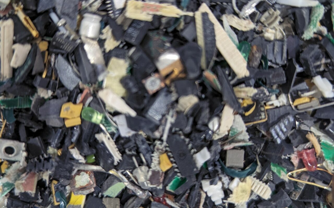 Amas de composants et de boîtiers en plastique noir issus d'appareils démontés, sur une aire de tri