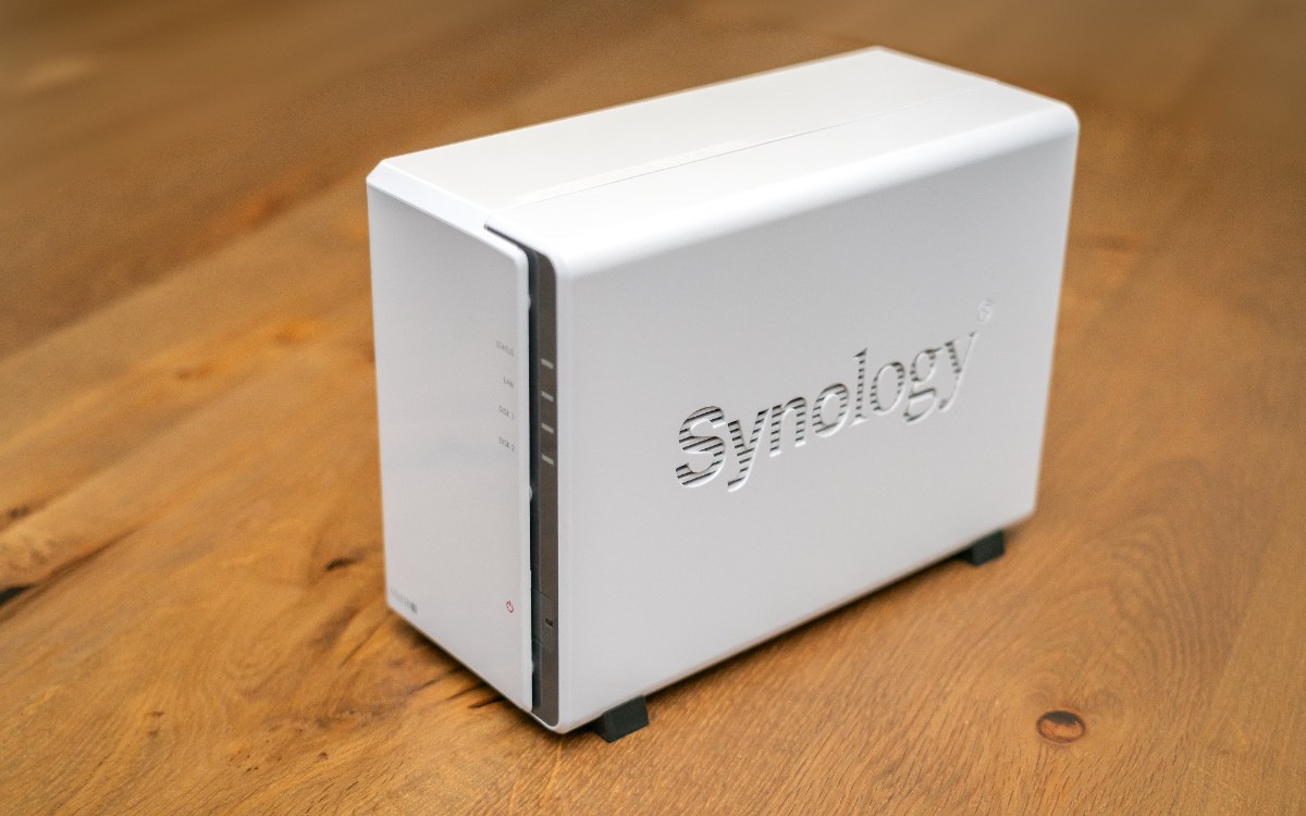 Petit boîtier NAS Synology blanc à 2 baies, posé sur un plateau en bois clair