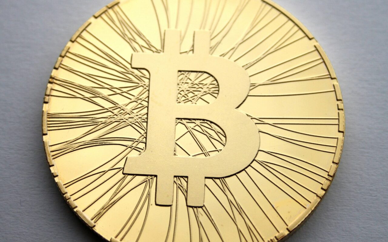 Piece metallique portant le symbole du bitcoin, posee sur une surface sombre