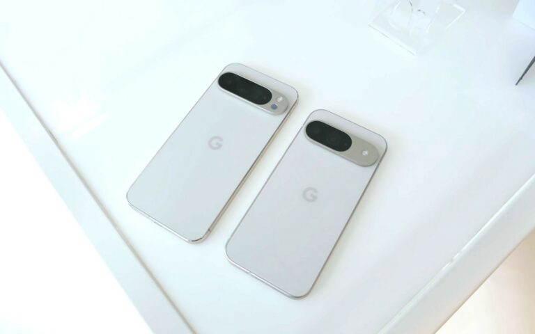 Deux smartphones Google Pixel 9 blancs posés côte à côte sur une table claire, dos vers le haut, barre photo et logo G visibles