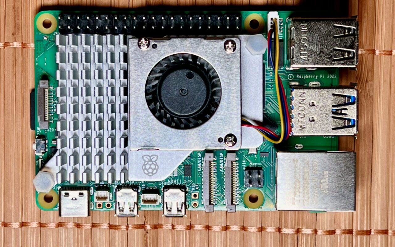 Carte Raspberry Pi 5 vue de dessus, avec dissipateur et ventilateur actif, posée sur un plan de travail en bois