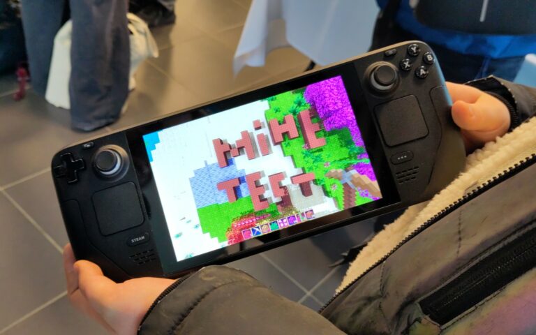 Console portable Steam Deck tenue à deux mains, affichant un jeu en pixel art