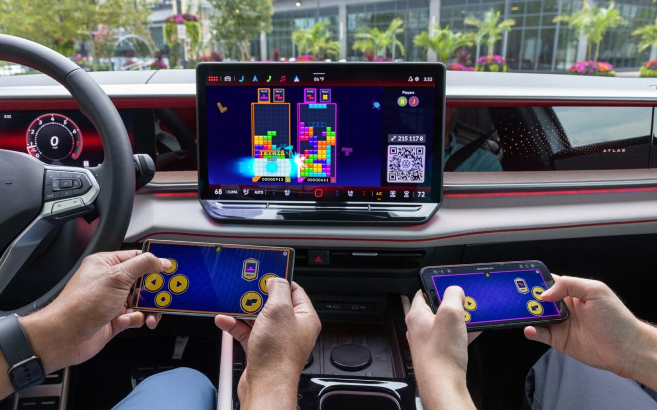 Tetris affiché sur l'écran central d'une Volkswagen, deux occupants jouant avec leur smartphone en manette