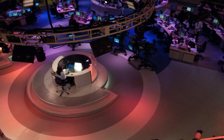 Salle de rédaction d'Al Jazeera English, avec des journalistes à leurs postes devant des écrans