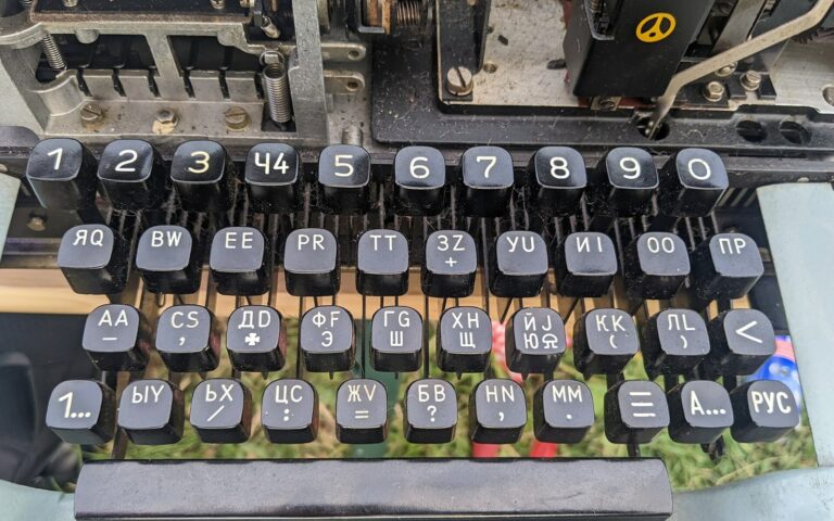Gros plan sur les touches rondes d'un téléimprimeur portant des lettres cyrilliques, dont plusieurs ressemblent à des lettres latines.