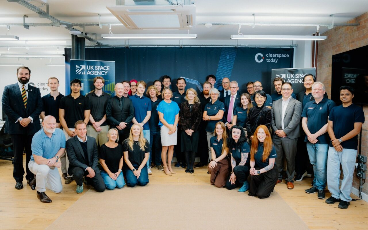 Une quarantaine de personnes posent en groupe dans un bureau, devant des bannières de l'agence spatiale britannique et de ClearSpace