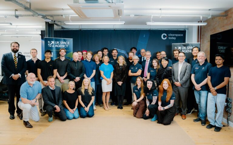 Une quarantaine de personnes posent en groupe dans un bureau, devant des bannières de l'agence spatiale britannique et de ClearSpace