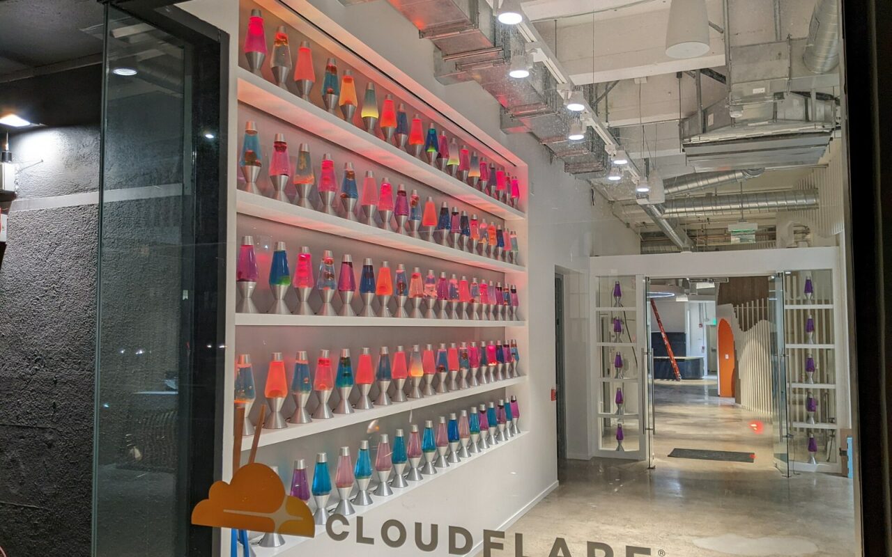 Des étagères de lampes à lave colorées dans le hall des bureaux de Cloudflare à San Francisco, le nom de l'entreprise inscrit au sol.