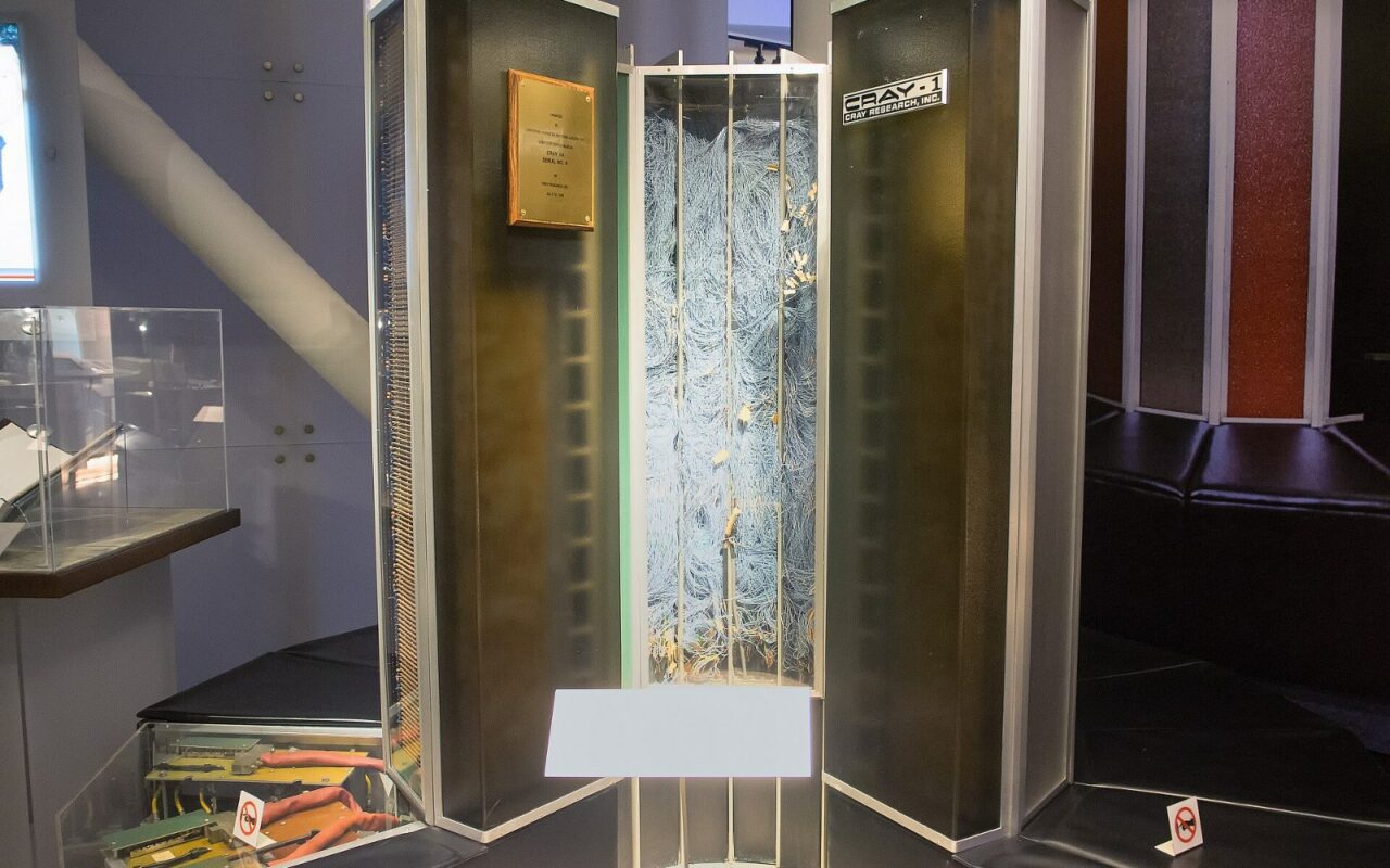 Un supercalculateur Cray-1 exposé dans un musée, un panneau ouvert laissant voir son câblage interne dense.
