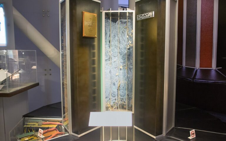 Un supercalculateur Cray-1 exposé dans un musée, un panneau ouvert laissant voir son câblage interne dense.
