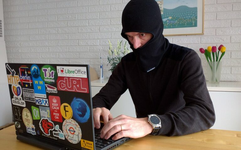 Daniel Stenberg, encagoulé pour la plaisanterie, tape sur un ordinateur portable couvert d'autocollants, dont celui de curl