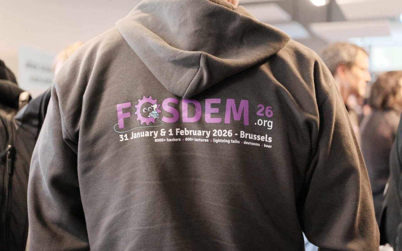 Un participant de dos portant un sweat gris FOSDEM 26 Bruxelles, dans une foule
