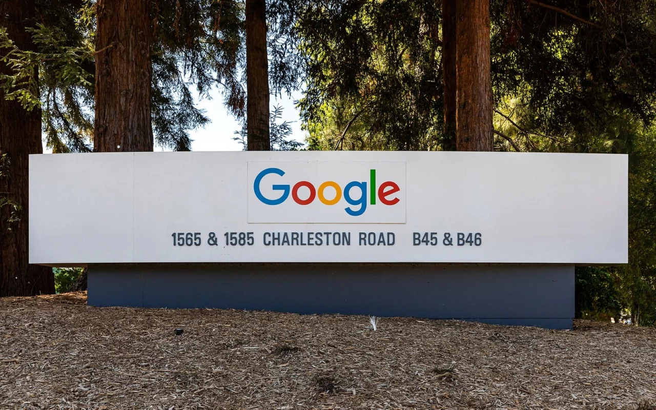 Panneau d'entrée d'un bâtiment de Google, avec le logo coloré et l'adresse Charleston Road, devant des séquoias à Mountain View