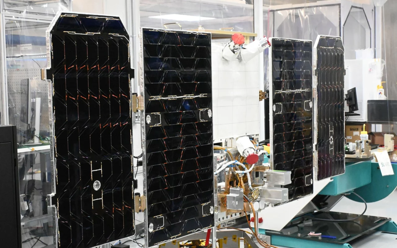 Le prototype de satellite Suncatcher, panneaux solaires noirs déployés, dans un atelier d'assemblage de Planet