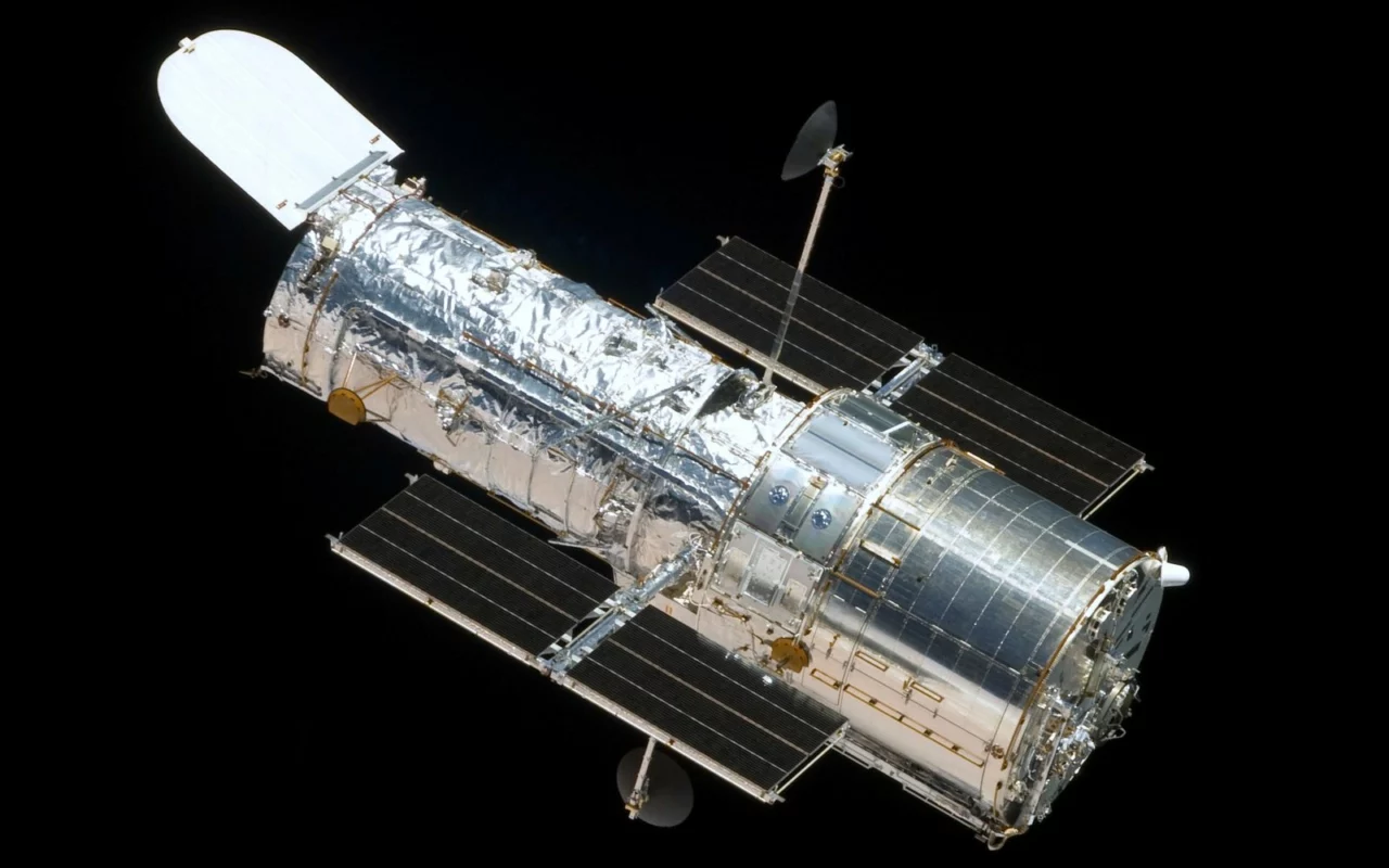 Le télescope spatial Hubble, cylindre argenté aux deux panneaux solaires déployés, flotte sur le fond noir de l'espace