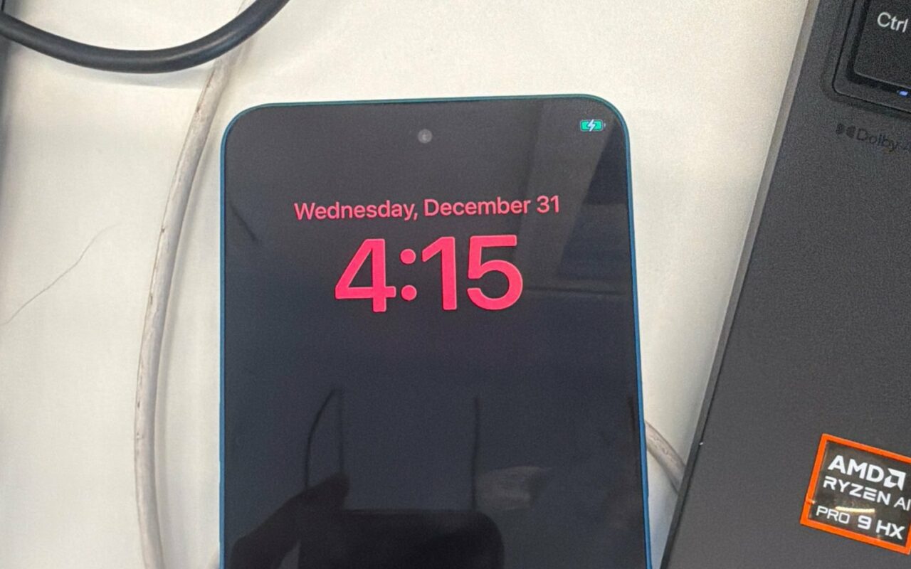 Smartphone Nothing posé sur un bureau, affichant l'écran de verrouillage d'iOS avec l'heure en rouge