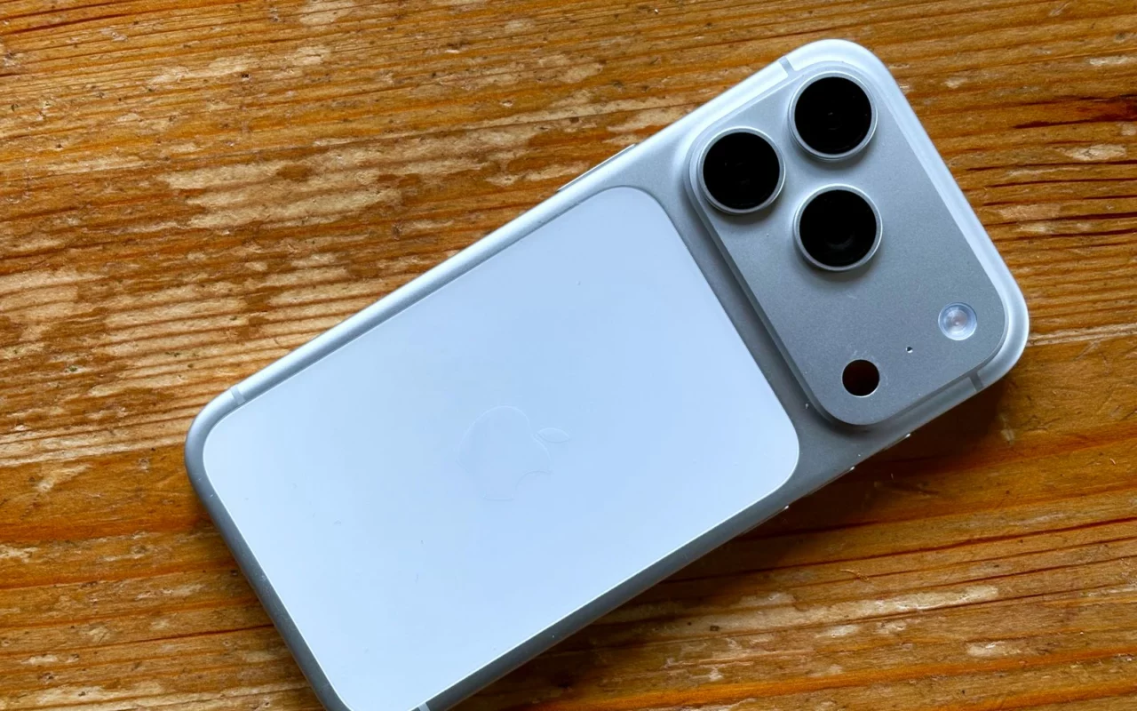 Un iPhone 17 Pro bleu clair posé face contre une table en bois, ses trois objectifs visibles