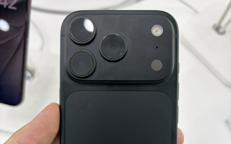 Un iPhone 18 Pro noir tenu en main, vu de dos avec son bloc de trois caméras