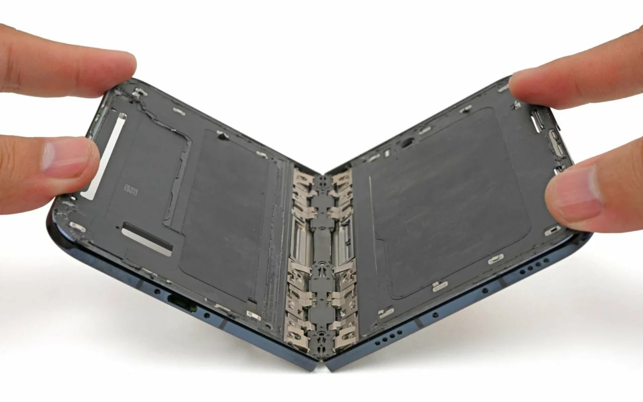Deux mains tiennent un iPhone Duo vidé de ses composants et à moitié ouvert, la charnière visible au centre