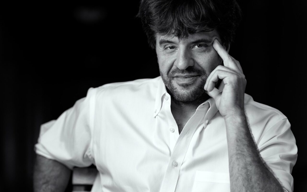 Portrait en noir et blanc de Karl Deisseroth, en chemise blanche, un doigt posé sur la tempe