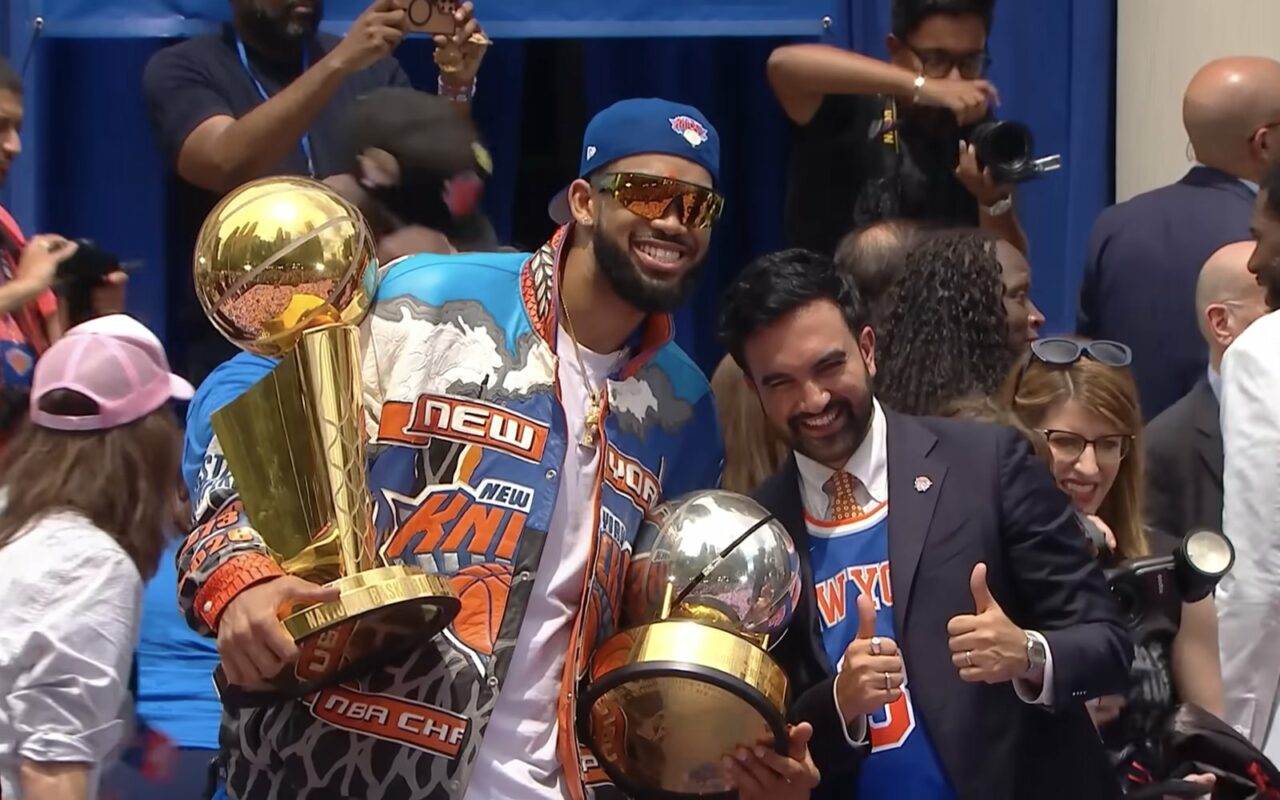 Un joueur des Knicks tient le trophée de champion NBA lors d'une cérémonie publique devant l'hôtel de ville de New York