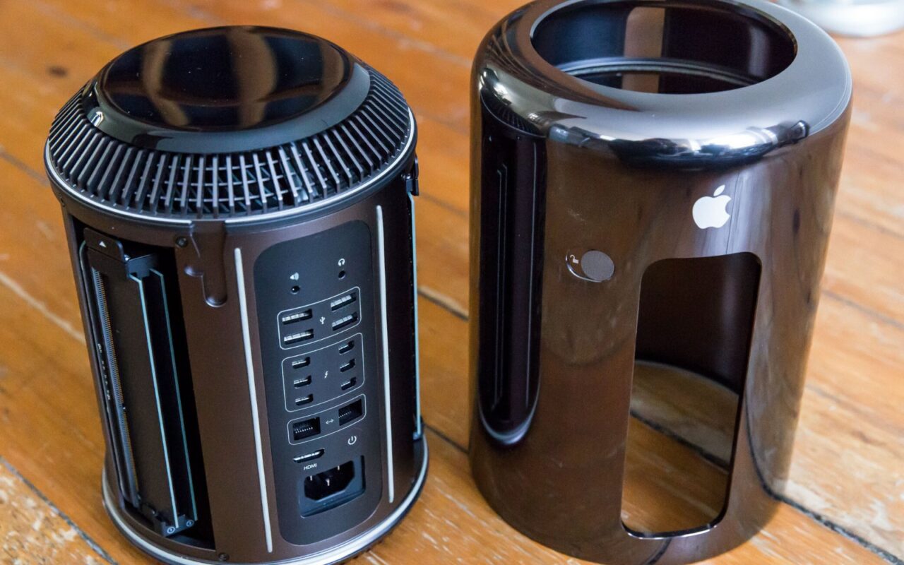 Un Mac Pro 2013 cylindrique noir, posé à côté de son capot en aluminium retiré