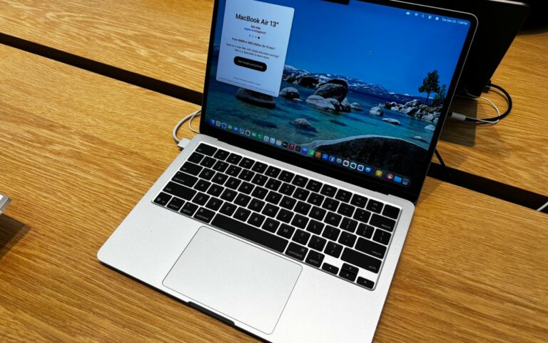 MacBook Air 13 pouces argenté ouvert sur une table en bois, écran allumé