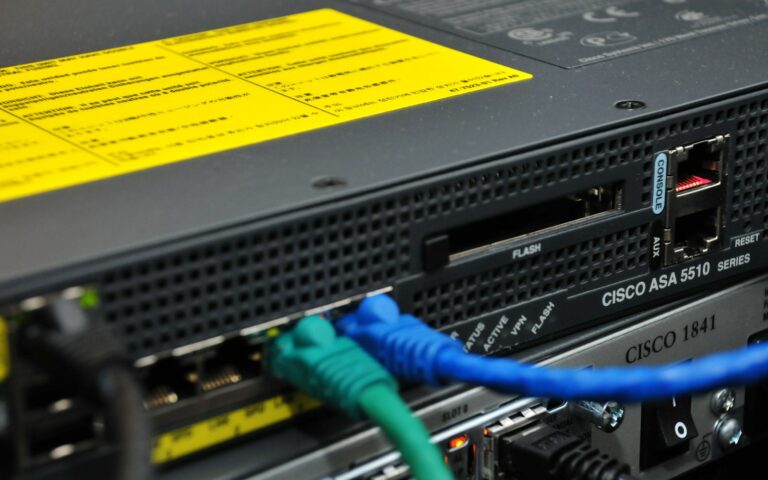 Pare-feu Cisco ASA 5510 monté en baie, avec des câbles réseau bleu et vert branchés en façade