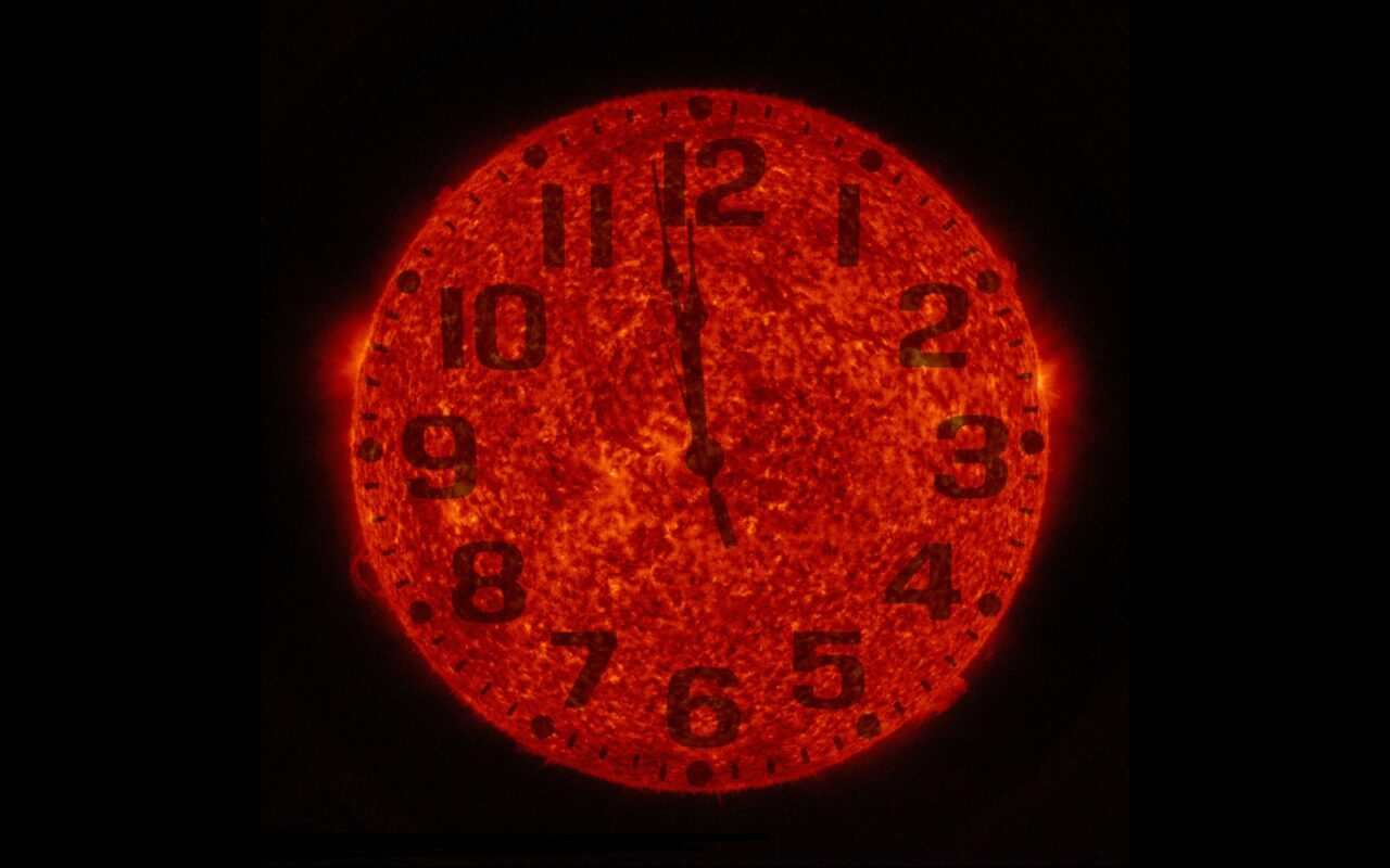 Image de la NASA : le disque orange du Soleil sert de cadran d'horloge, aiguilles juste avant midi, sur fond noir