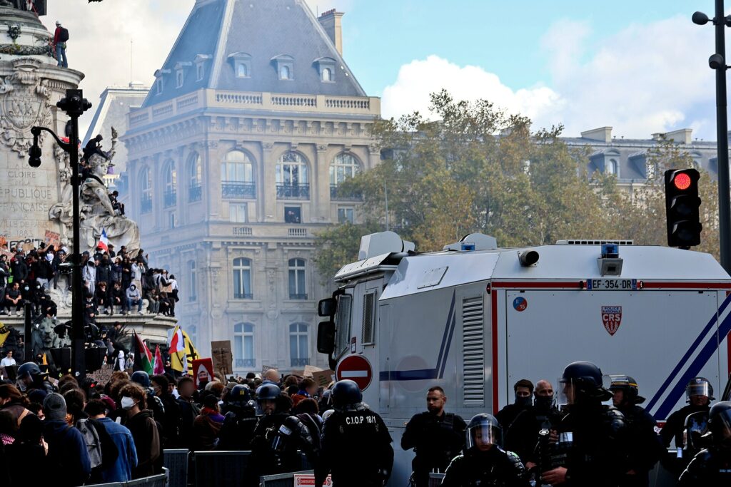 Foule de manifestants sur la place de la République à Paris, devant un véhicule blindé de la police équipé d'un canon à eau