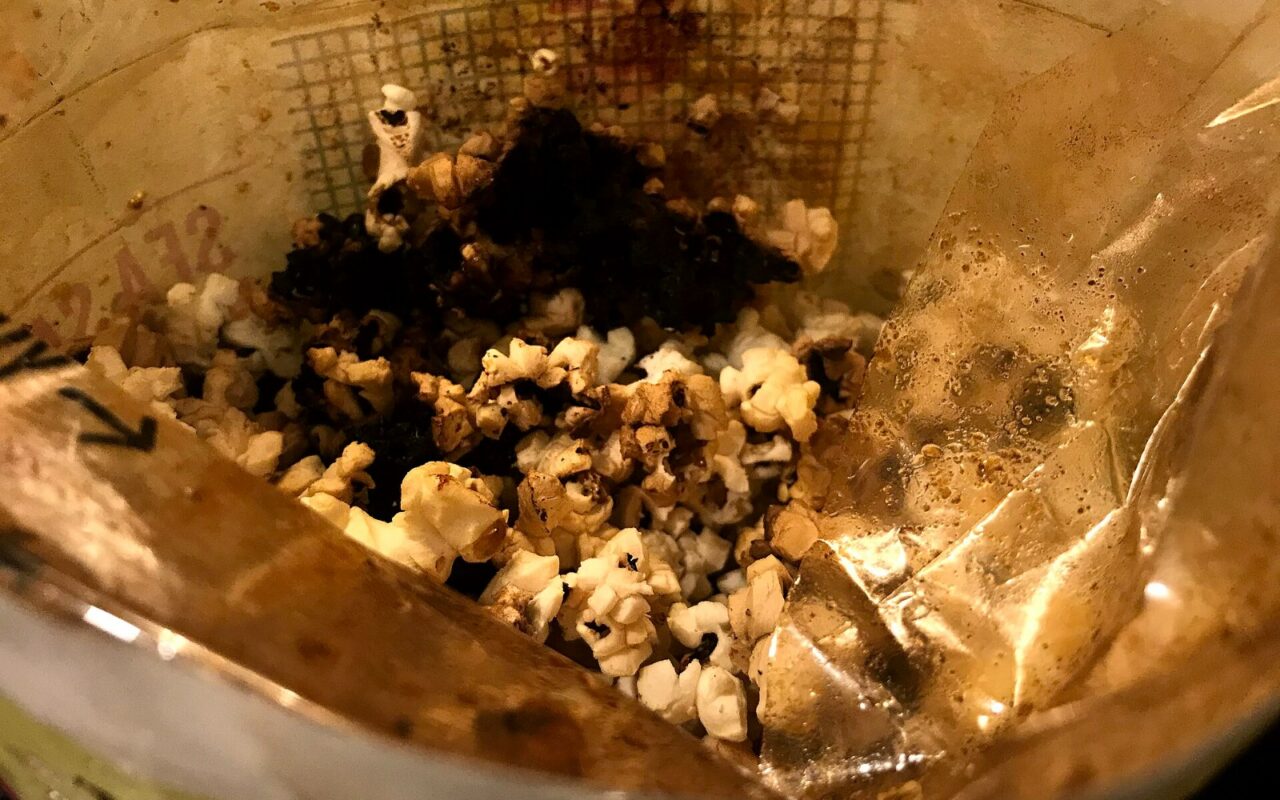 Un sachet de popcorn ouvert dont le contenu est en partie carbonisé, noir au centre.