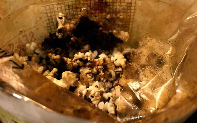Un sachet de popcorn ouvert dont le contenu est en partie carbonisé, noir au centre.
