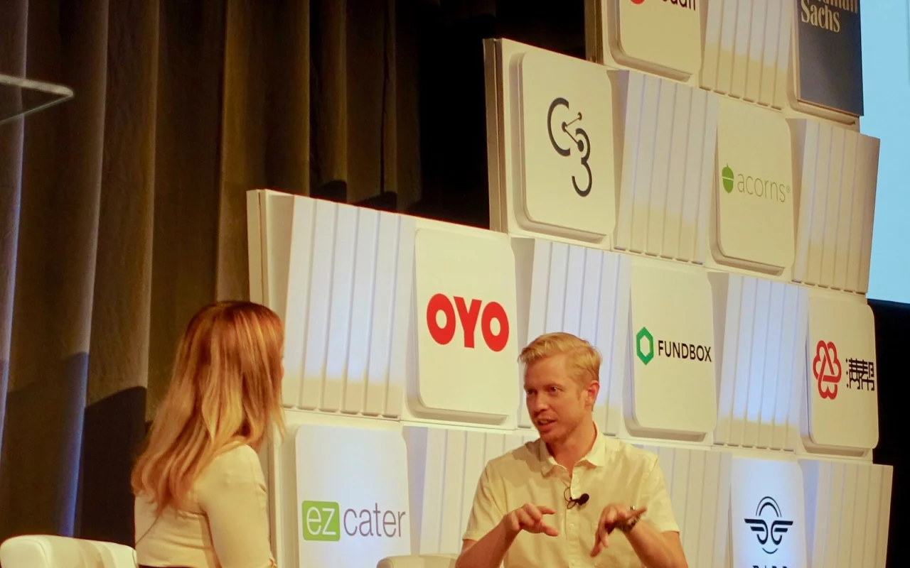 Steve Huffman, patron de Reddit, assis sur une scène, parle en faisant un geste des mains face à une interlocutrice