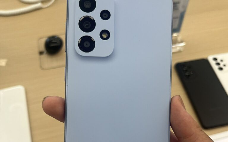 Dos bleu clair d'un Samsung Galaxy A33 5G tenu en main, avec ses quatre caméras