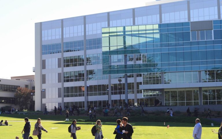 Vue du campus de l'université d'État de San Francisco : une pelouse, des étudiants et la bibliothèque J. Paul Leonard vitrée.