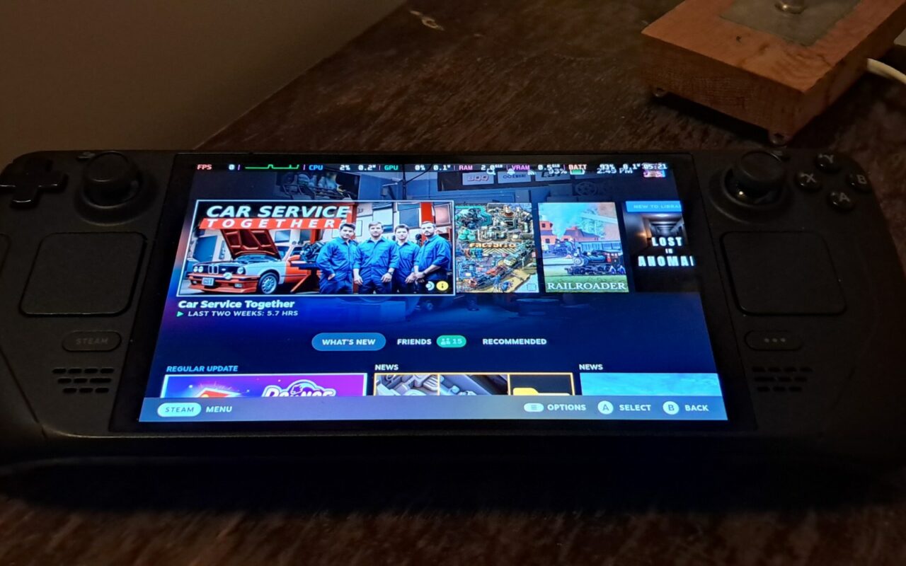 Un Steam Deck OLED posé sur une table, écran allumé sur l'accueil de Steam