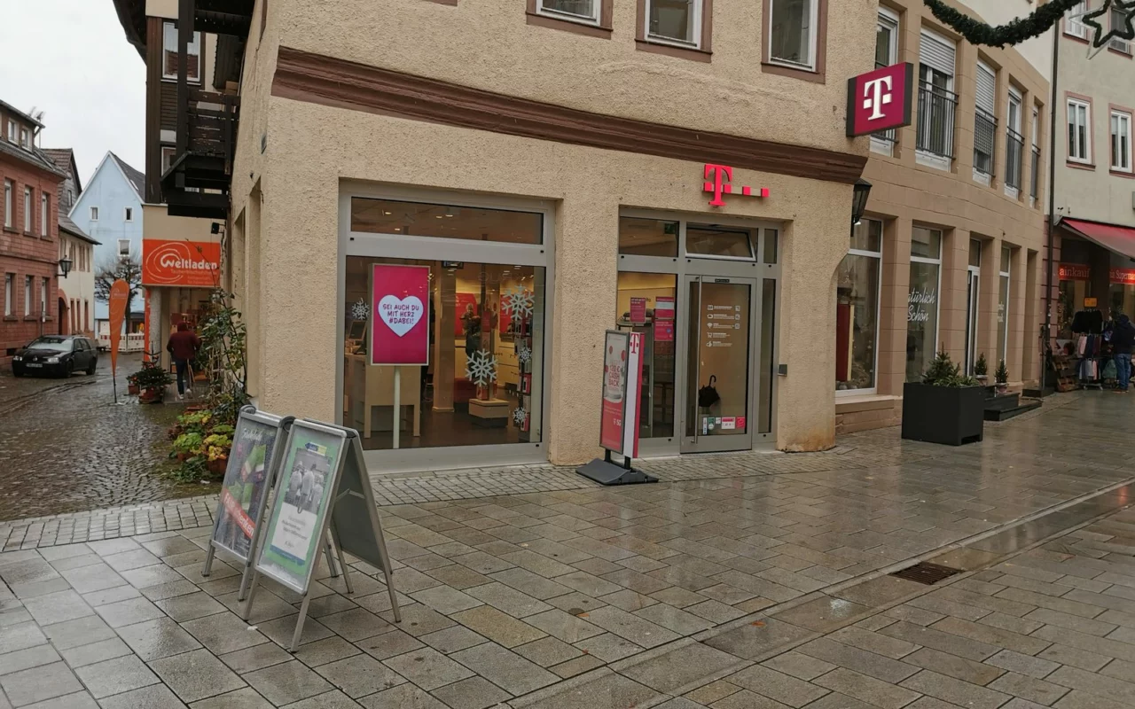 Façade d'une boutique Telekom avec le logo magenta, dans une rue pavée