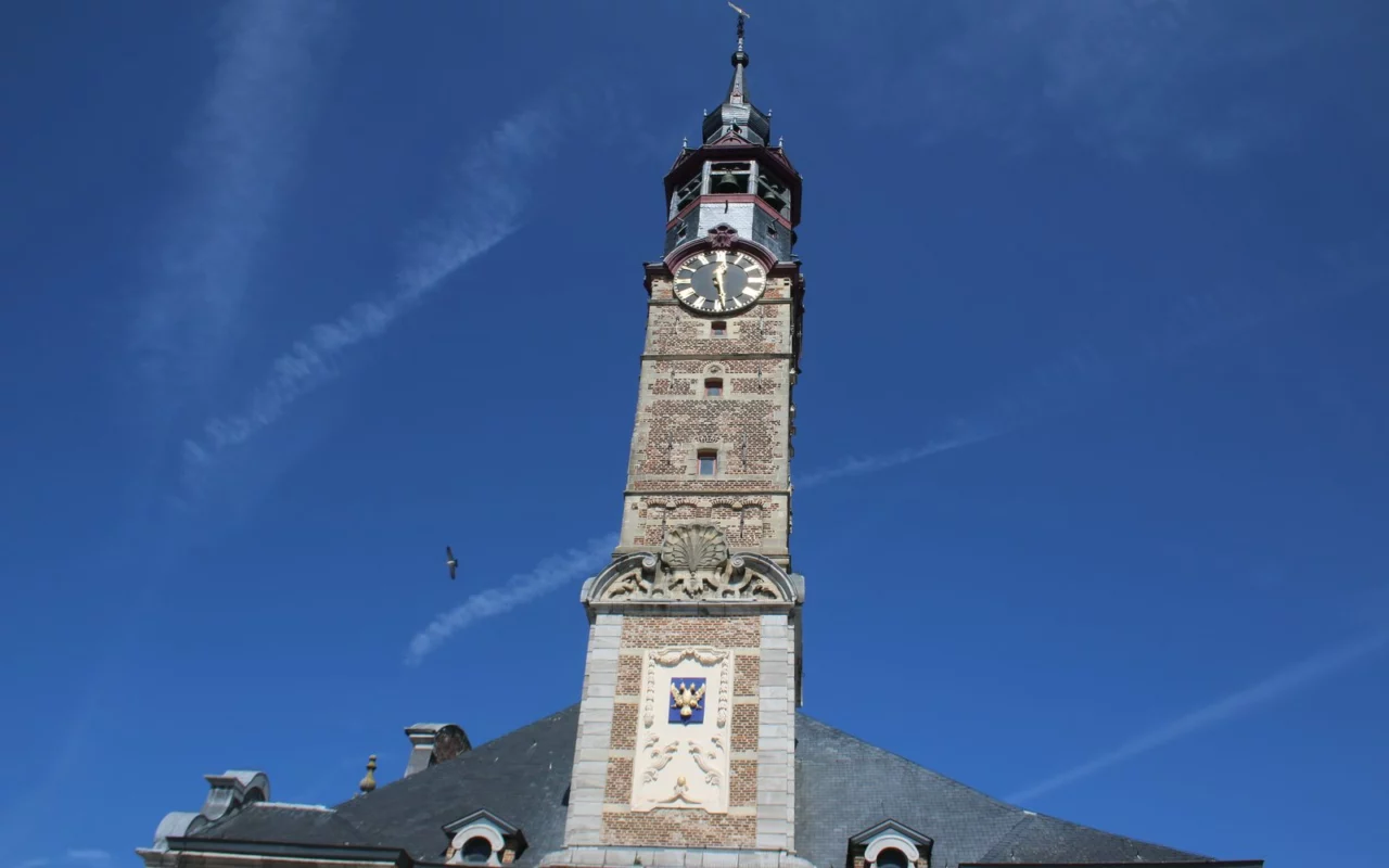 Le beffroi de l'hôtel de ville de Saint-Trond, avec son horloge, sous un ciel bleu